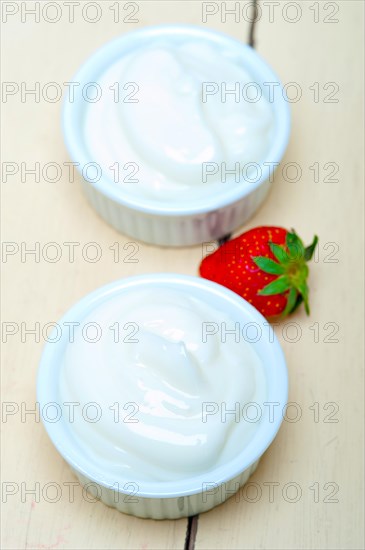 Organic Greek yogurt and strawberry over white rustic wood table