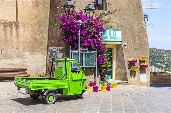 Green Piaggio Ape utility vehicle in front of the cathedral of Rio nell Elba