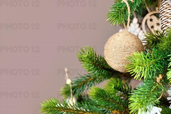 Christmas tree branches with natural ornament bauble made from beige jute robe with copy space