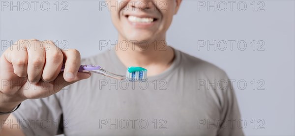 Young man showing toothbrush with toothpaste isolated