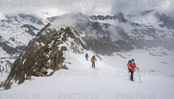 Ski tourers walking on the rope on the glacier in winter in the mountains