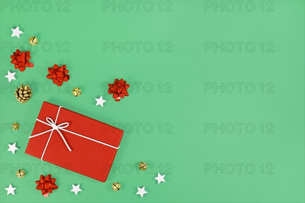 Red Christmas gift box surrounded by golden seasonal pine cones