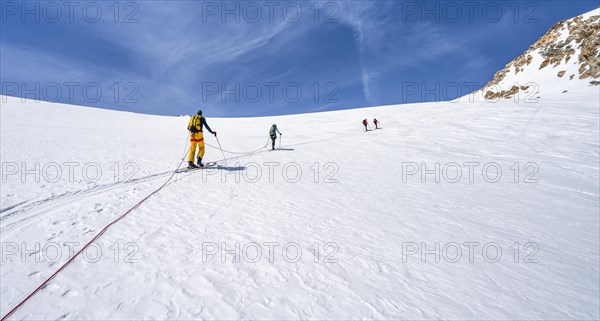 Ski tourers walking on the rope on the glacier