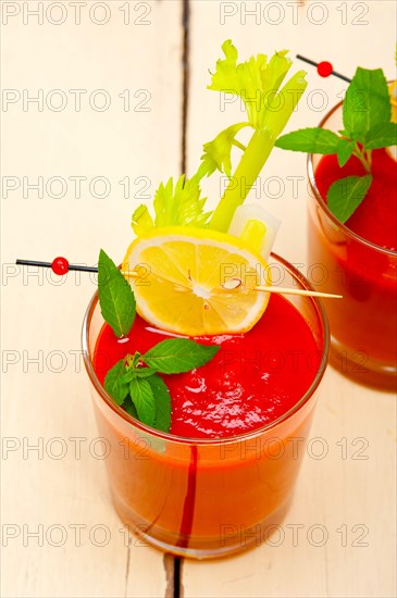 Fresh tomato juice gazpacho soup on a glass over white wood table