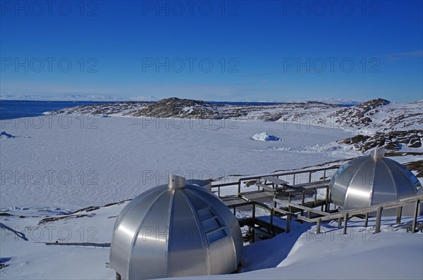 Futuristic metal igloo shelters in a wintry landscape