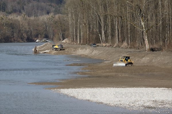 An excavator and a caterpillar reshape the banks of a river