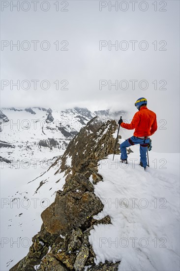 Ski tourers on rocky ridge with snow