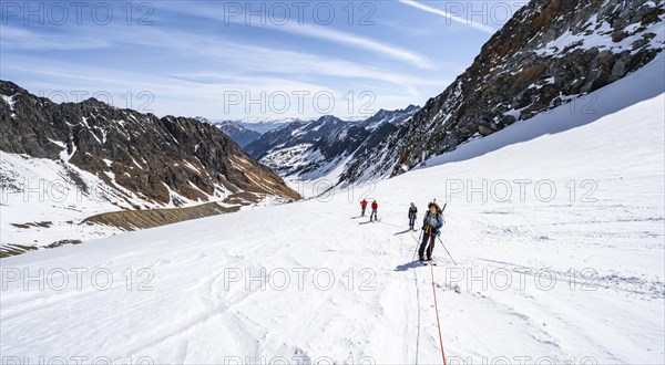 Group of ski tourers walking on the rope on the glacier