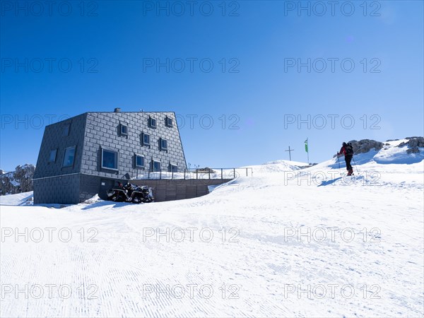 Snowshoe hiker in front of mountain hut