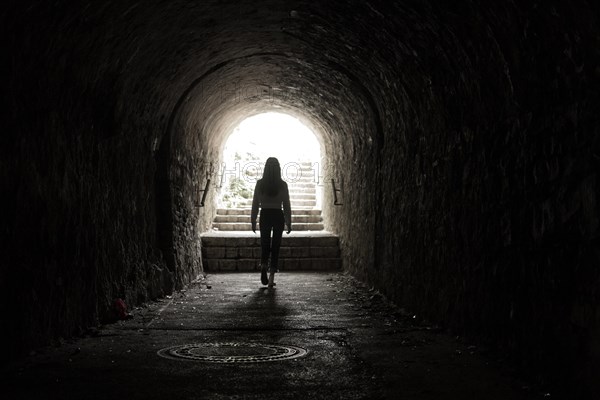 Girl walking throug dark tunnel into light