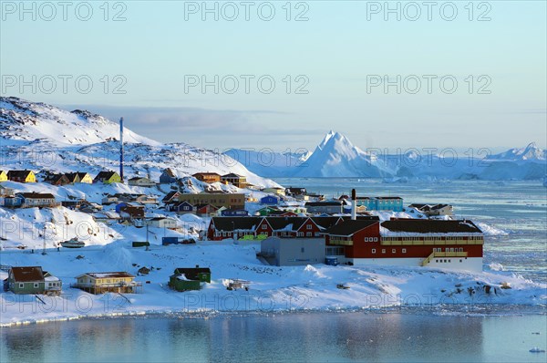 Homes and public buildings in front of huge icebergs