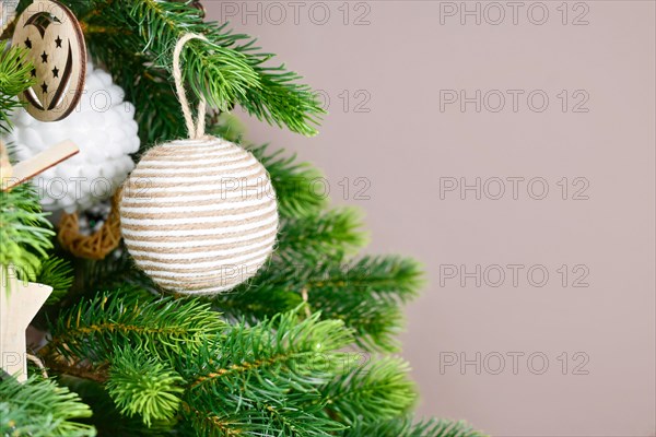 Christmas tree branches with natural ornament bauble made from beige jute rope with copy space