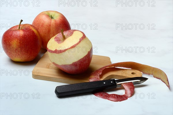 Peeled apple and apple peel with paring knife