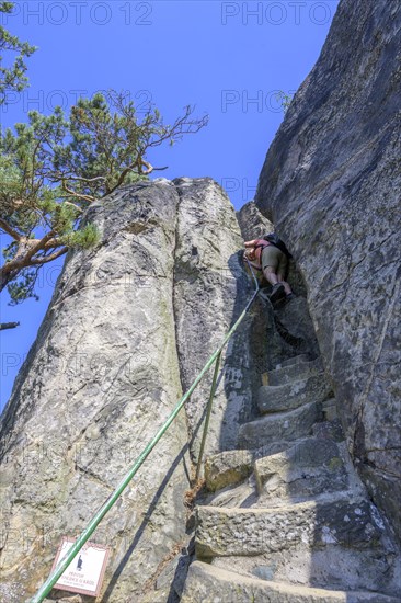 Woman descending steep stairs from the lookout point of the rock castle Vranov