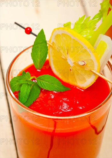 Fresh tomato juice gazpacho soup on a glass over white wood table