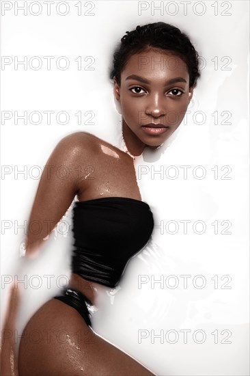 Beautiful african american woman with classic makeup in milk bath. Beauty face