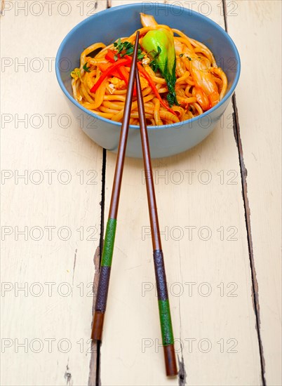 Hand pulled stretched Chinese ramen noodles on a bowl with chopstick