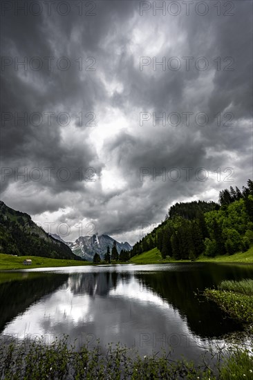 Groeppelensee with reflection of the Altmann summit in the background under a threatening cloudy sky