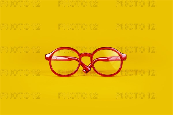 Small red round eye glasses on yellow background