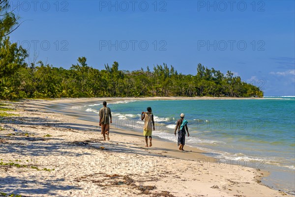Workers walking on a long white sand beach in the east of the island Ile Sainte-Marie although Nosy Boraha