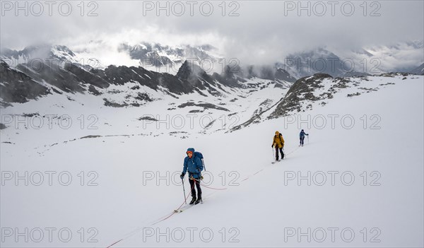 Ski tourers walking on the rope on the glacier in winter in the mountains