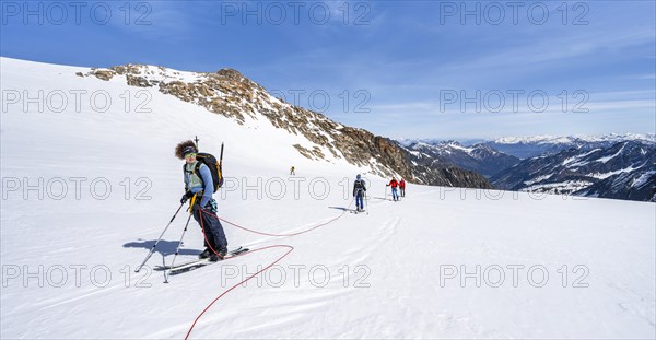 Ski tourers walking on the rope on the glacier