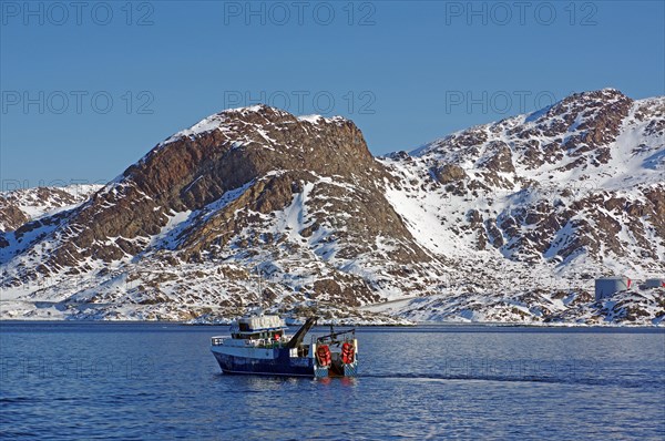 Modern fishing vessel in barren rocky landscape in winter