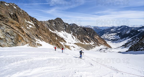 Three ski tourers walking on the rope on the glacier