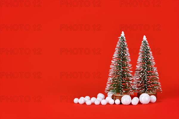 Miniature Christmas trees and snowballs on red background with copy space