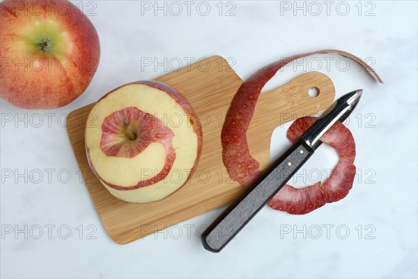 Peeled apple and apple peel with paring knife