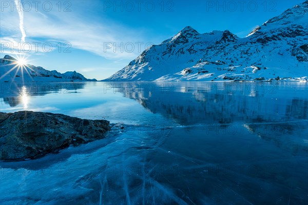 Ice structures and rock in the black ice of the frozen Lago Bianco in the Swiss mountains