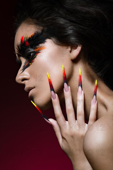 Beautiful girl in the image of the Phoenix bird with creative makeup and long nails. Manicure design. The beauty of the face. Photos shot in studio