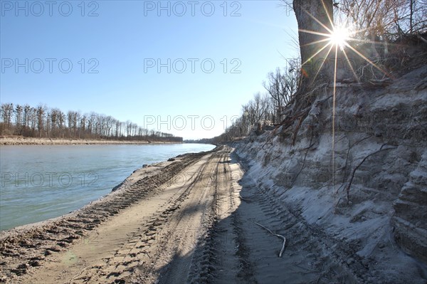 Steep wall of sand and dredge marks on a river bank