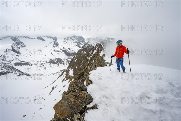 Ski tourers on rocky ridge with snow