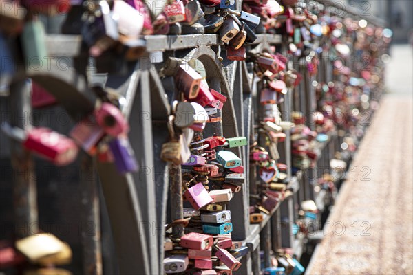 Very many colourful love locks hang on a bridge railing