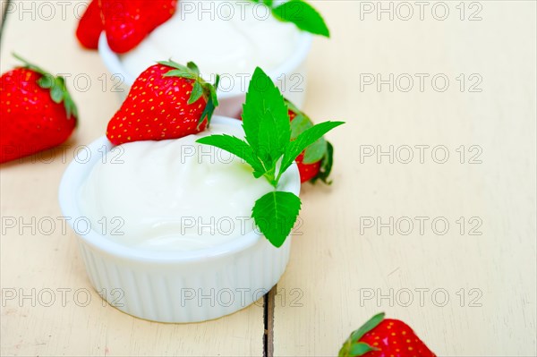 Organic Greek yogurt and strawberry over white rustic wood table