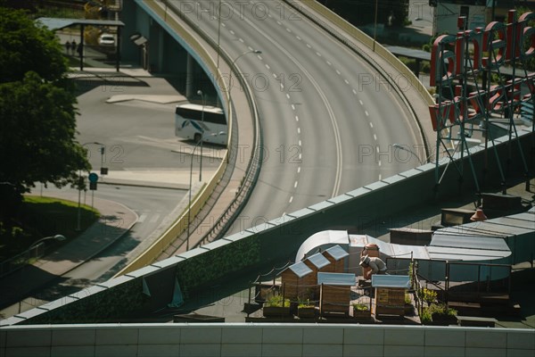 A beekeeper at the hives on the roof of a building in the city