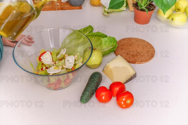 Above view of a woman adding olive oil to a healthy salad at her kitchen table