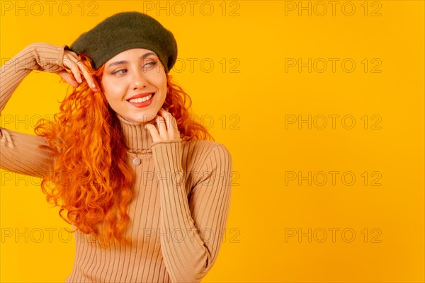 Red-haired woman in beret in studio on a yellow background