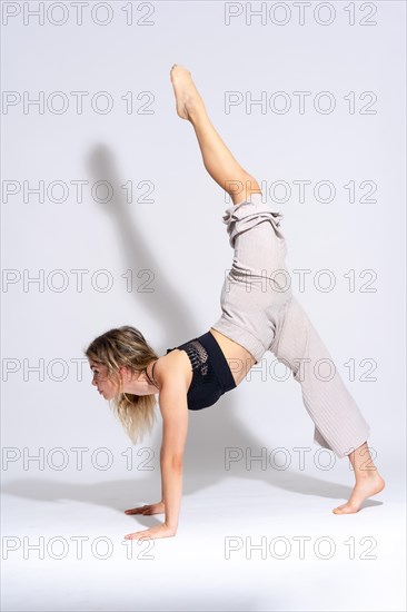 Portrait of young dancer in the studio raising her leg on a white background