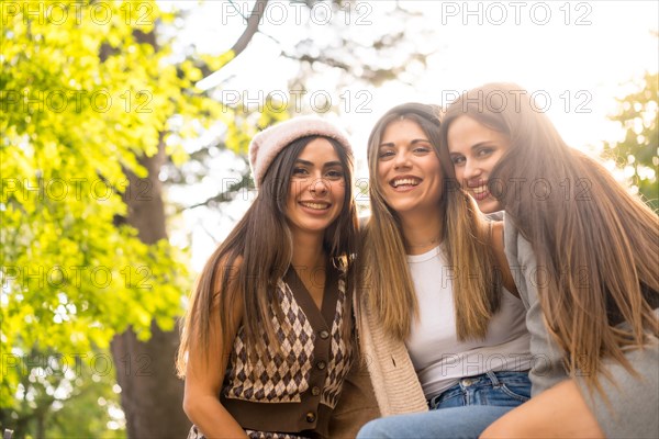 Women friends sitting in a park in autumn