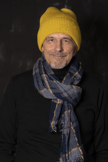 Older man with yellow cap and scarf