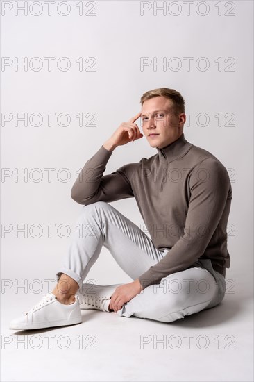 Portrait of an attractive blond Caucasian model in a brown sweater on a white background