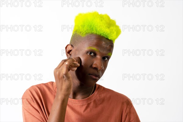 An androgynous black man posing putting on makeup