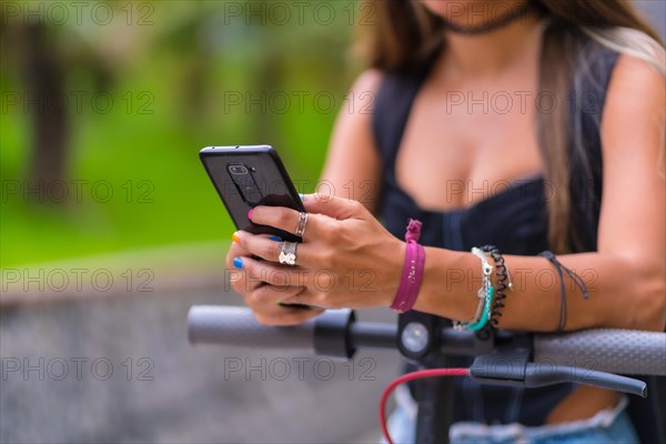 Detail of a young woman on an electric scooter talking on the phone