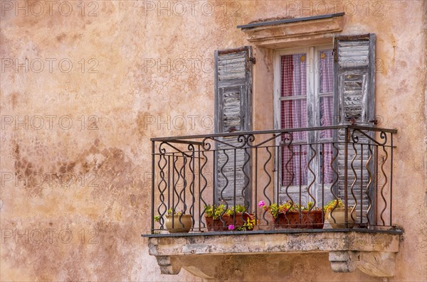 Balcony with old shutters on weathered house facade