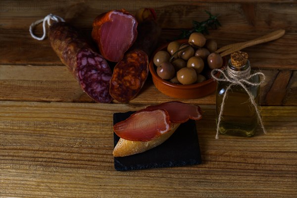 Tapa of iberian loin on rustic bread with olive oil on a black slate with black background