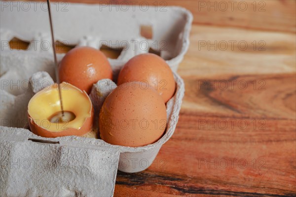 Woman beating an egg in its own shell with a small blender