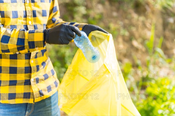 Unrecognizable person collecting plastics in a forest. Ecology concept