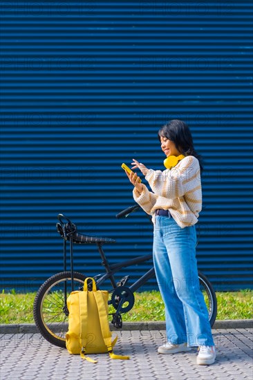 Asian college student girl listening to music with yellow headphones on a blue background
